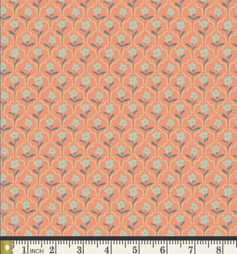 May include: Coral-colored fabric with a repeating floral pattern. The design features light blue flowers with gray stems and leaves, set against a backdrop of a scalloped, yellow-gold outline. The fabric is measured with a ruler in inches.