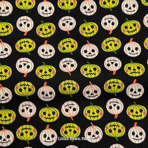 May include: A black fabric featuring a repeating pattern of stylized jack-o'-lanterns in alternating white and lime green colors. Each pumpkin has a simple face with black eyes, a nose, and a jagged mouth, with small pink circles on the cheeks.