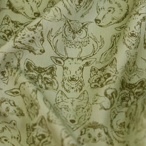 May include: Light green fabric with a repeating pattern of woodland animal illustrations in a darker green. The design includes bears, foxes, owls, deer, wolves, raccoons, and squirrels. The fabric has a slightly wrinkled texture.