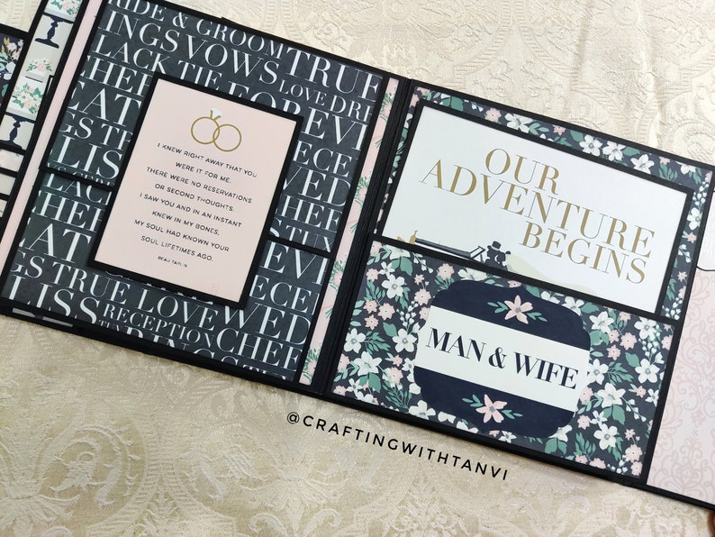 May include: A black and white scrapbook with a pink and green floral pattern. The scrapbook is open to reveal a page with the text "Our Adventure Begins" and "Man & Wife". The page also features a quote about love and marriage.