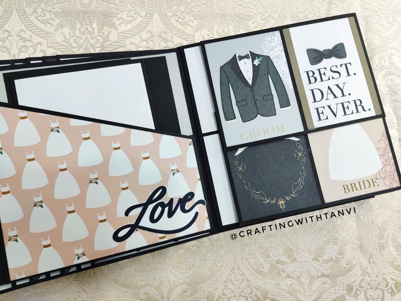 May include: A black scrapbook with a pink and white patterned page featuring a white dress design. The scrapbook has a black page with the word "Love" in white lettering. The other pages have a black background with white text that says "Groom" and "Bride". One page has a black bow tie and the text "Best Day Ever".