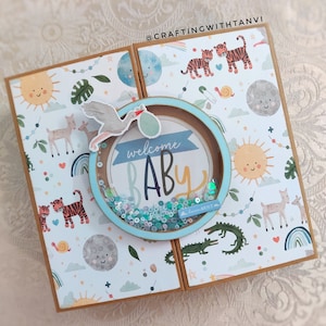 May include: A blue and brown card with a shaker element that says "welcome baby" inside. The card has a white background with a jungle animal print.