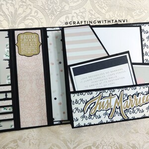 May include: A black and white wedding scrapbook with a pink and white patterned background. The scrapbook is open to reveal a pocket with a quote about love and a card that says "Just Married".
