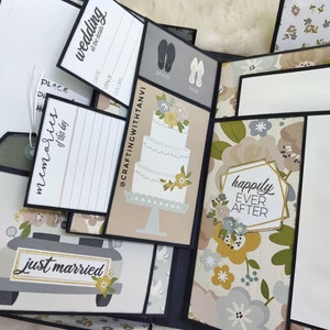 May include: A wedding scrapbook featuring a floral design and the text "happily ever after". The scrapbook has several pages with different designs, including a wedding cake, a car with the text "just married", and a page with the text "wedding all the details".