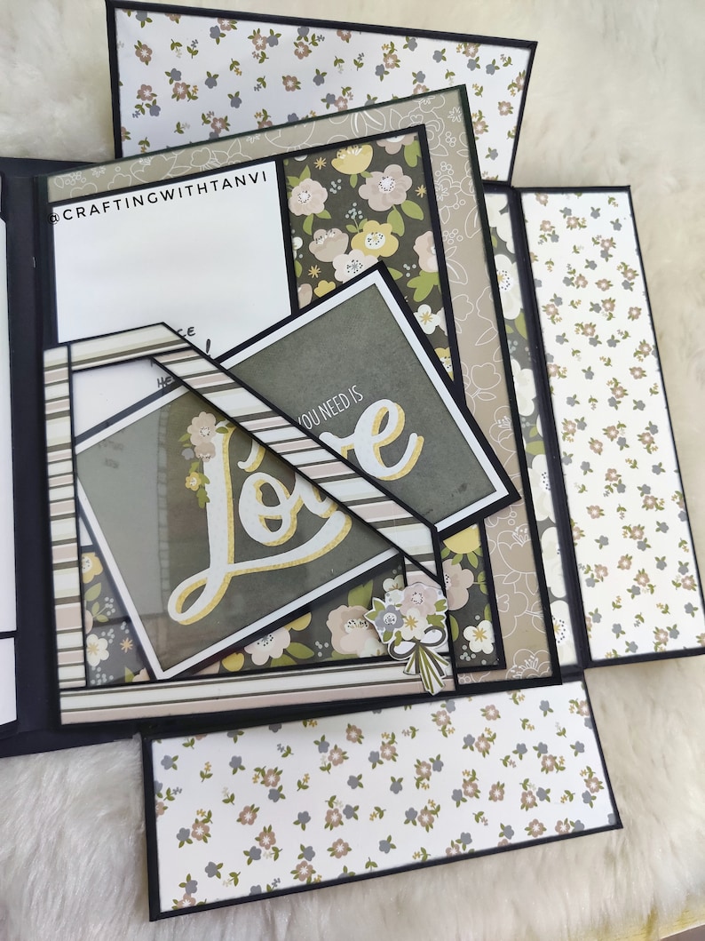 May include: A multi-layered scrapbook with a floral pattern and the word "Love" in gold lettering. The scrapbook is decorated with a floral bouquet and the text "You need is".