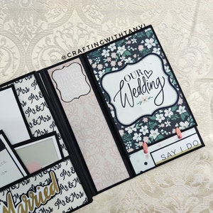 May include: A black and white wedding scrapbook with a floral design and the text "Our Wedding" and "Say I Do".