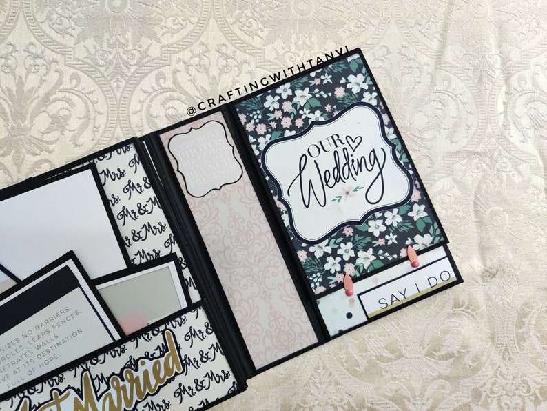 May include: A black and white wedding scrapbook with a floral design and the text "Our Wedding" and "Say I Do".