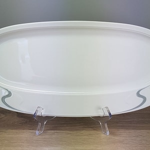 Könnte beinhalten: Weiße ovale Servierplatte mit einem grauen, wellenförmigen Design am Rand.