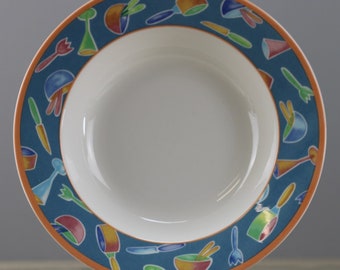 May include: A white ceramic soup bowl with a blue and orange rim. The rim is decorated with colorful cartoon images of kitchen utensils and food.