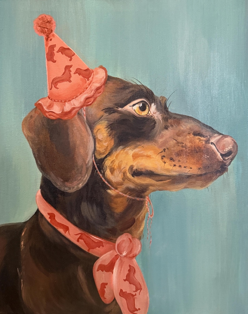 May include: A portrait of a dachshund wearing a party hat and a scarf, both adorned with dachshund silhouettes. The dog has brown and black fur, with a light blue background. The party hat is coral with a pom-pom on top.