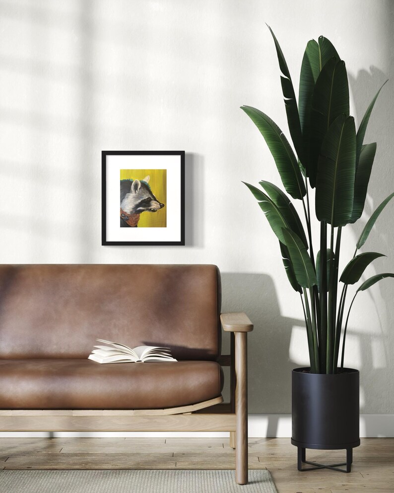 May include: A framed print of a raccoon with a yellow background. The raccoon is looking to the right of the frame. The frame is black and has a white mat.