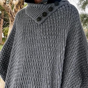 May include: A gray knitted poncho with a high collar and button closure. The poncho has a textured knit pattern.