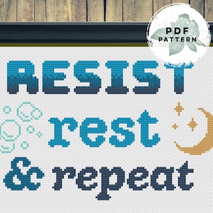 May include: Cross-stitch pattern with the words "RESIST rest & repeat" in blue and teal pixelated text. Includes a crescent moon and stars in gold, and bubbles. The words are on a white background.