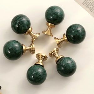 Peut inclure: Six boutons de porte ronds en marbre vert et en laiton. Les boutons ont une finition en marbre vert avec des accents en laiton doré.