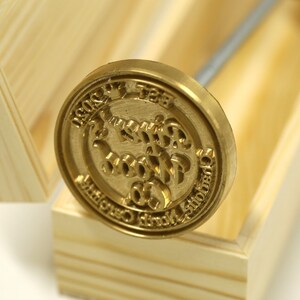 May include: A gold-colored metal stamp with the text "1920" and "1957" on the top and bottom of the stamp. The text "The Little Wood Co." is in the center of the stamp. The stamp is in a wooden box.