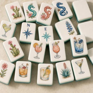 May include: A collection of rectangular mahjong tiles featuring colorful illustrations of cocktails, cacti, flowers, dragons, and compass directions labeled with N and E. Each white tile has a smooth finish and displays detailed artwork of drinks with garnishes, desert plants, and mythical creatures.