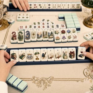 May include: A Mahjong set featuring tiles with intricate illustrations of books, flowers, landscapes, and vintage objects. The tiles are arranged on a game board with a rack holding numbered tiles from one to nine, each displaying a unique graphic.