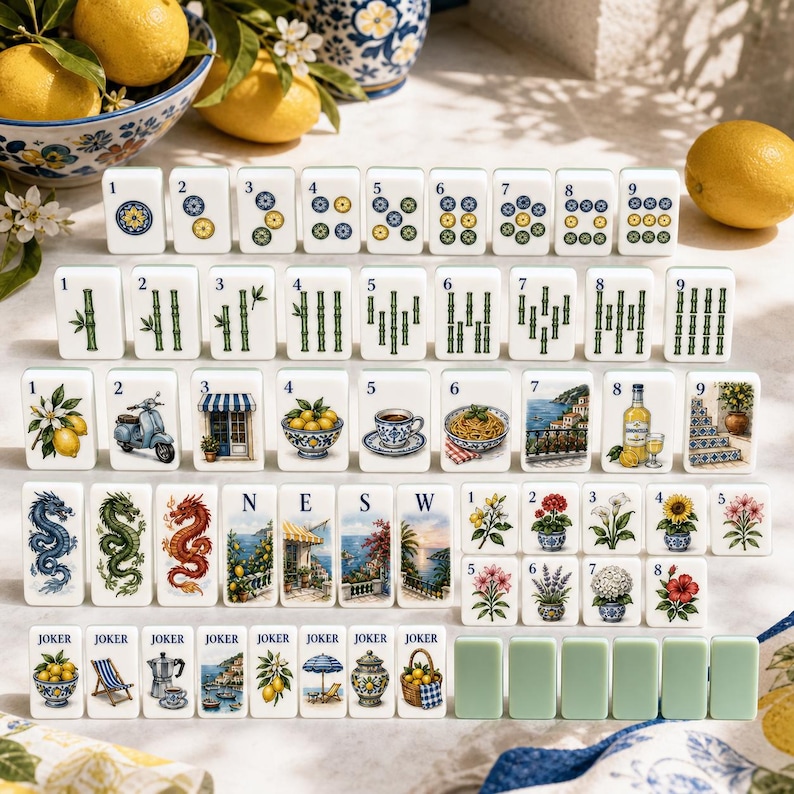 May include: A set of white mahjong tiles featuring colorful illustrations of lemons, coastal scenes, flowers, dragons, and bamboo patterns. The collection includes numbered tiles, directional tiles labeled N, E, S, W, and Joker tiles with various designs.