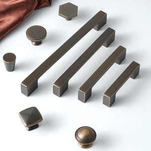 May include: Assortment of antique brass cabinet hardware, including knobs and pulls in various shapes and sizes.
