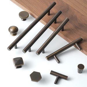 May include: Assortment of antique bronze cabinet hardware, including knobs and pulls in various shapes and sizes.