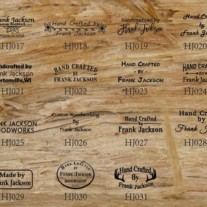 May include: A collection of 11 different wood-burning stamps featuring the text "Hand Crafted by Frank Jackson" in various styles and fonts. The stamps are arranged in a grid on a wood background. The stamps are numbered HJ017 through HJ031.