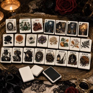 May include: A set of rectangular mahjong tiles featuring intricate illustrations of skulls, flowers, pumpkins, and gothic scenes. Several tiles are labeled with text including SOAP, GREEN, RED, N, E, S, W, and JOKER. The tiles are white with black backs.