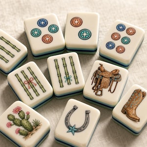 May include: A collection of off-white Mahjong tiles featuring various illustrations including bamboo stalks, compass-like circles, a brown leather saddle, a brown cowboy boot, a horseshoe with a blue star, and a green cactus with pink flowers.