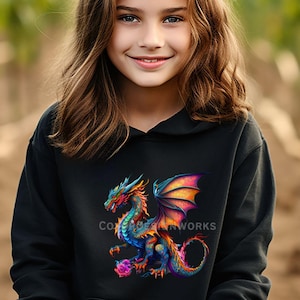 May include: Black hooded sweatshirt featuring a colorful dragon design. The dragon has blue, orange, red, and purple hues. The text "COXBEAR ARTWORKS" is printed on the sweatshirt. The background is blurred.