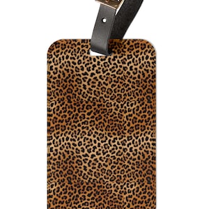 May include: A brown and black leopard print luggage tag with a black leather strap and a gold buckle.