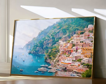 May include: A colorful painting of a coastal town built into a hillside overlooking a blue ocean. The town is a mix of yellow, orange, red, and white buildings. The hillside is covered in green trees and shrubs. The ocean is a bright blue with whitecaps.