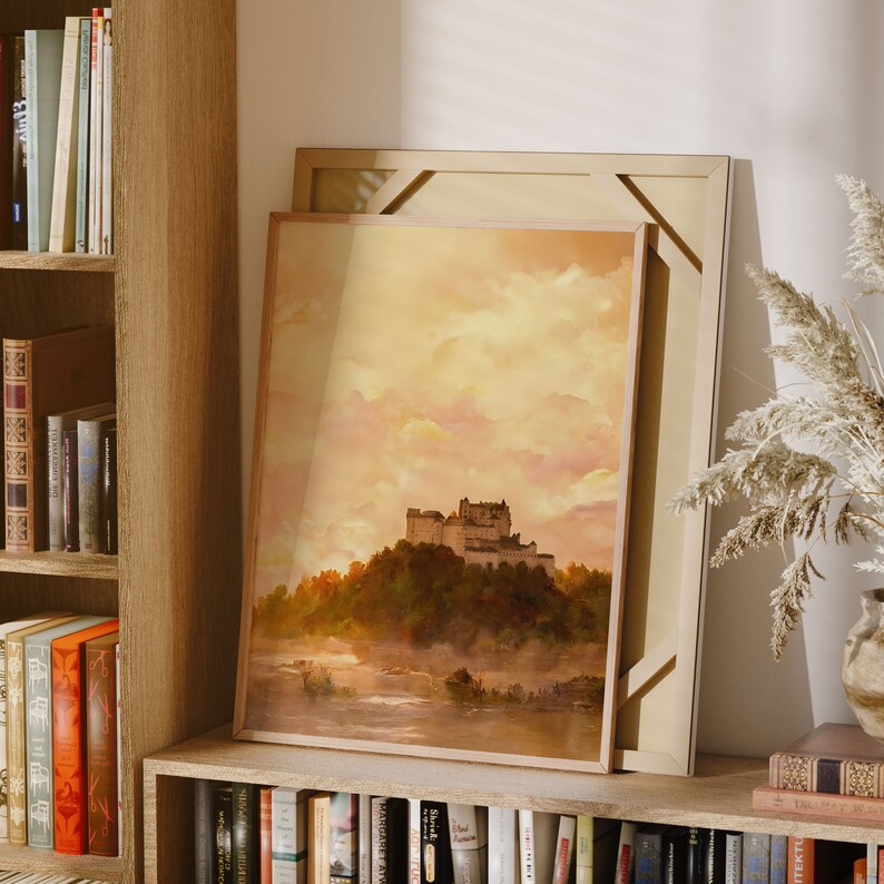 May include: A framed painting of a castle in a misty landscape. The castle is surrounded by trees and the sky is a soft yellow and pink.