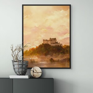 May include: A framed watercolor painting of a castle on a hill with a misty river in the foreground. The sky is a soft orange and pink.