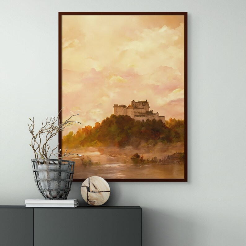 May include: A framed watercolor painting of a castle on a hill with a misty background. The castle is white with a brown roof and is surrounded by green trees. The sky is a soft yellow and orange.