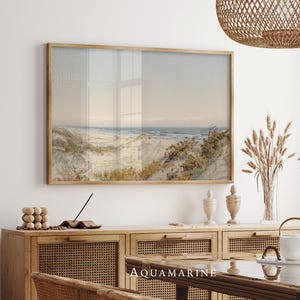 Antique style coastal landscape painting with rolling sand dunes, wild grasses and a quiet shoreline stretching toward the horizon. Soft beige, blue and earthy tones blend in a vintage watercolor illustration printed with visible paper texture, evoking a peaceful seaside scene and timeless coastal wall art aesthetic.
