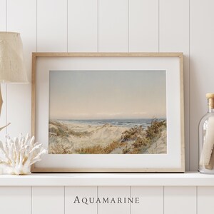 Vintage seaside landscape artwork depicting sandy dunes, coastal vegetation and gentle waves along a tranquil beach. The soft watercolor style, faded vintage tones and visible antique paper texture create a refined natural scene perfect for coastal decor, beach house interiors or classic landscape wall art.
