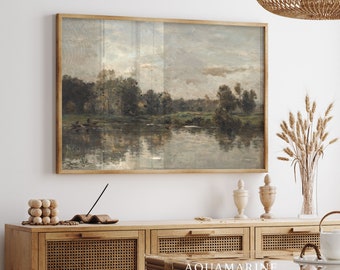 May include: A framed landscape painting depicts a serene river scene with trees and a cloudy sky. The artwork is displayed above a wooden cabinet with decorative items, including a vase of wheat and a glass vase with branches. The room is decorated in neutral tones.