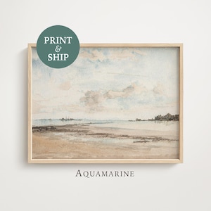 Könnte beinhalten: Ein gerahmter Aquarelldruck einer Küstenlandschaft. Das Kunstwerk zeigt eine Strandszene mit hellblauem Himmel, Wolken und einem sandigen Ufer. Der Druck trägt die Aufschrift "Aquamarine" und enthält eine "Print & Ship"-Grafik.