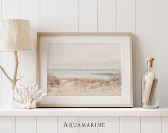 May include: A framed landscape print with a beach scene in muted tones of beige, blue, and brown. The artwork is displayed on a white shelf with a lamp, coral, and a decorative bottle. The word "AQUAMARINE" is printed at the bottom.