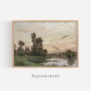 Puede incluir: Una impresi&oacute;n enmarcada de un paisaje que presenta una serena escena de r&iacute;o con un peque&ntilde;o bote, &aacute;rboles y una casa. La obra de arte tiene una paleta de colores apagados de verdes, marrones y azules, con la palabra "AQUAMARINE" impresa en la parte inferior.
