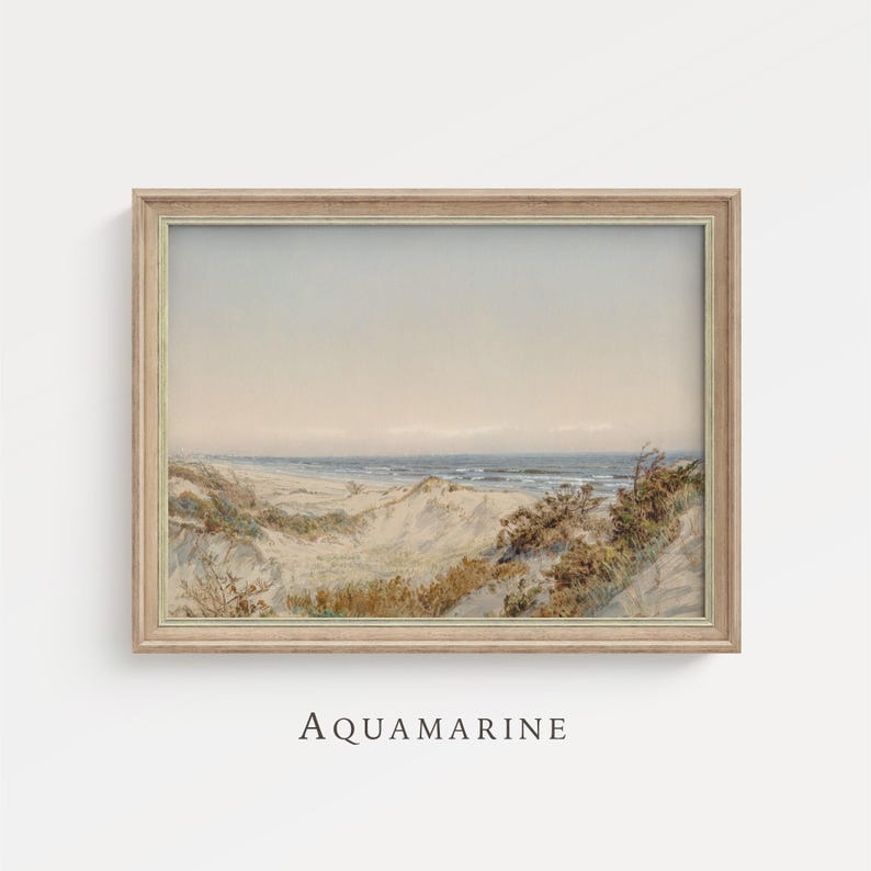 May include: A framed watercolor print of a beach scene. The artwork depicts sand dunes, ocean waves, and a pale sky. The frame is a light wood color, and the text "AQUAMARINE" is printed at the bottom.