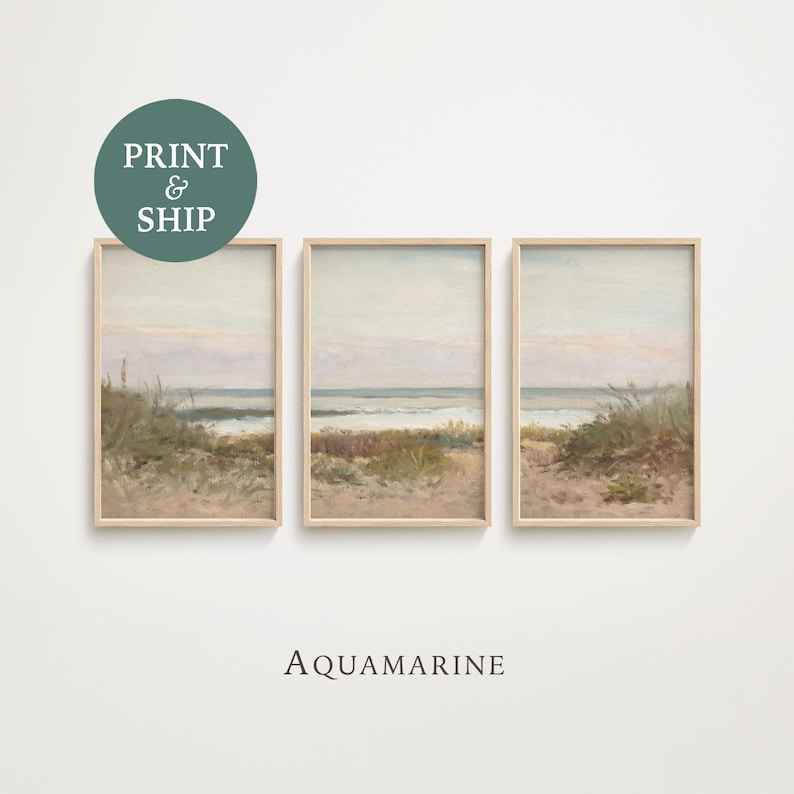 May include: Three framed beach landscape prints. Each print features a coastal scene with sand, sea, and sky in muted tones. The artwork is in a light wood frame. The text "AQUAMARINE" is below the prints.
