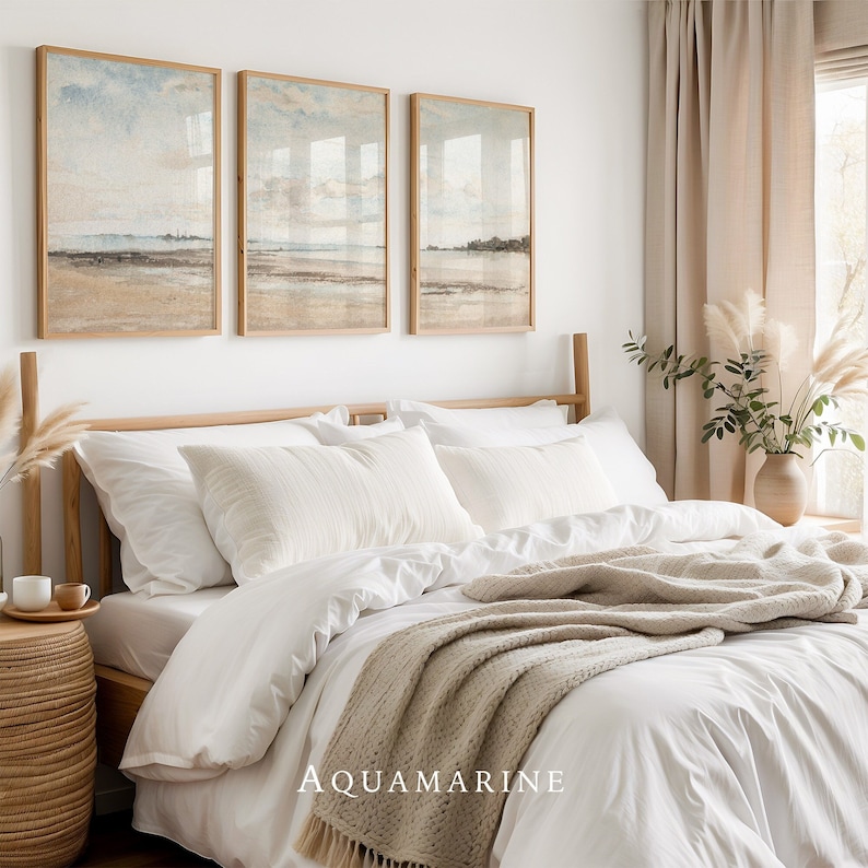 May include: A bedroom scene featuring a bed with white bedding, pillows, and a beige throw blanket. Above the bed are three framed landscape prints with a beach theme. The word "AQUAMARINE" is printed at the bottom of the bed.