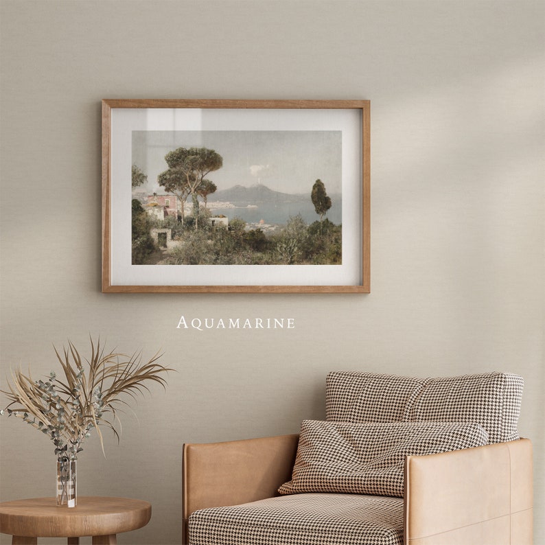 May include: A framed print of a landscape painting depicting a lush green hillside with a small house and trees in the foreground. The background features a distant mountain range and a body of water. The print is titled "AQUAMARINE".
