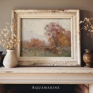 May include: A framed landscape painting with a distressed white frame. The artwork depicts a fall scene with trees in shades of red, orange, and yellow. The painting is displayed on a white mantel with decorative vases and dried flowers.
