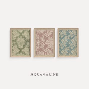 May include: Three framed prints with floral patterns in shades of green, pink, and blue. The prints have a vintage aesthetic, with ornate designs and a distressed look. The frames are a light wood color. The word "AQUAMARINE" is printed below the frames.