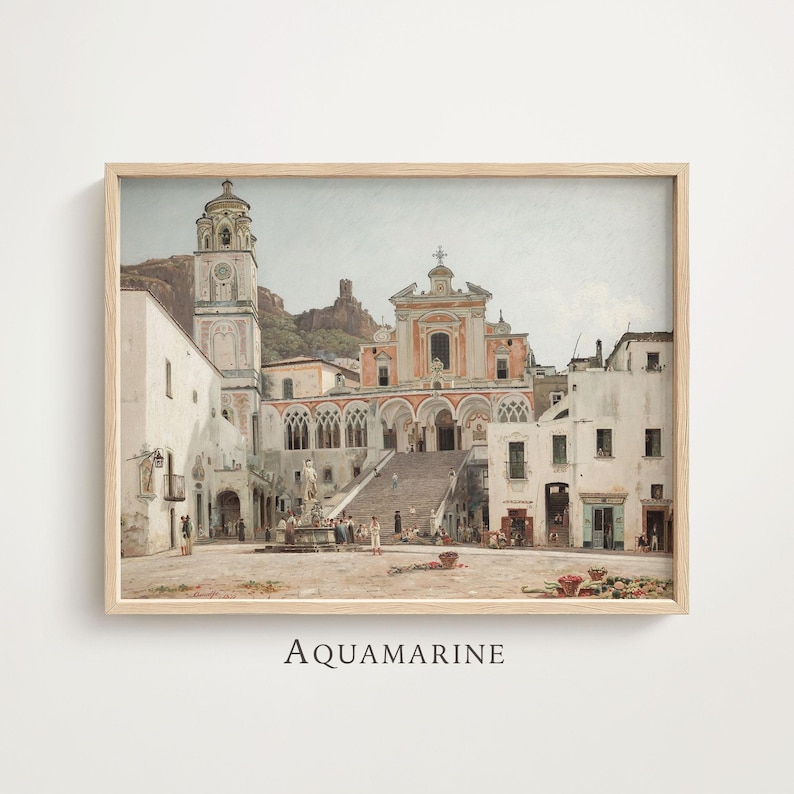 May include: A framed art print depicting a Mediterranean town square with a large church, a tall bell tower, and a central fountain. The scene features white buildings, stone stairs, and a mountain backdrop in muted tones of beige, gray, and terracotta.