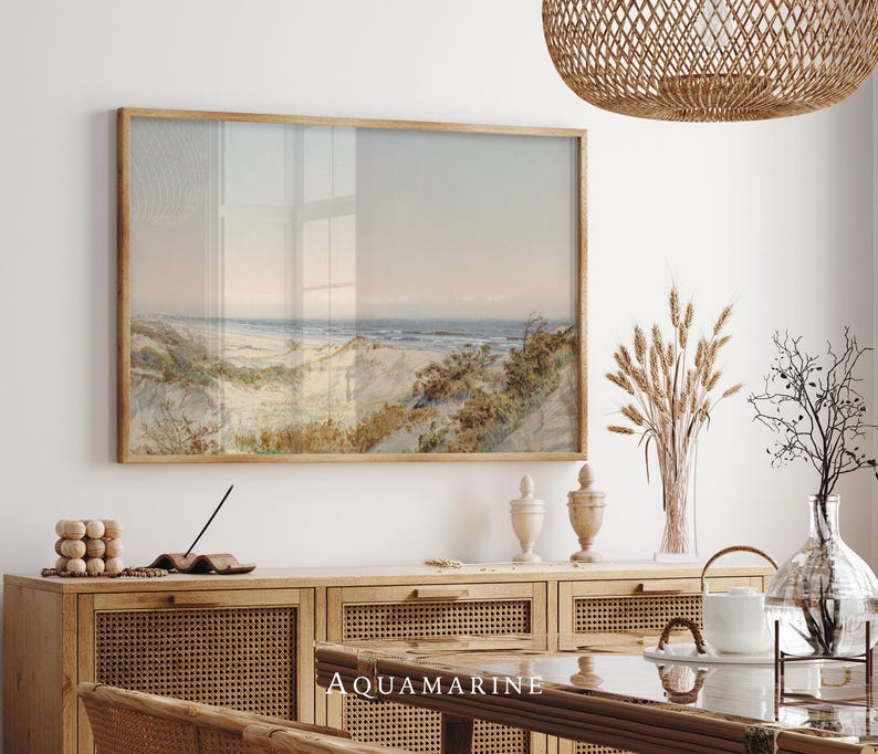 Antique style coastal landscape painting with rolling sand dunes, wild grasses and a quiet shoreline stretching toward the horizon. Soft beige, blue and earthy tones blend in a vintage watercolor illustration printed with visible paper texture, evoking a peaceful seaside scene and timeless coastal wall art aesthetic.