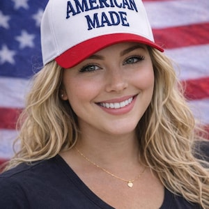 May include: A white baseball cap with a red brim and the text "AMERICAN MADE" in blue. The cap is worn in front of an American flag.