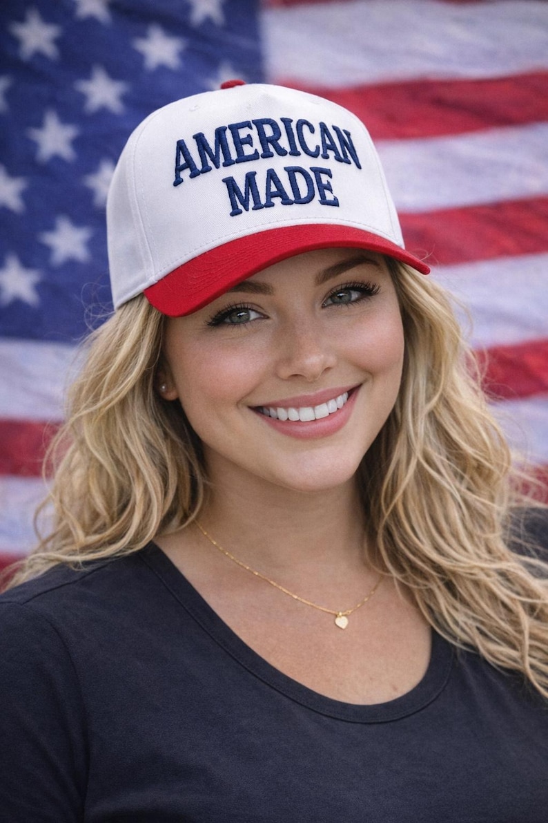 May include: A white baseball cap with a red brim and the text "AMERICAN MADE" in blue. The cap is worn in front of an American flag.