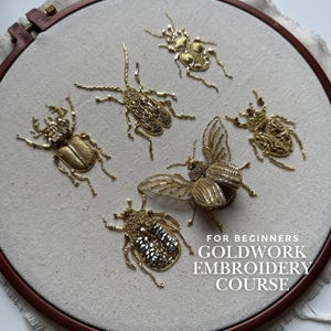 May include: A goldwork embroidery course for beginners, showcasing six golden beetle designs on cream fabric. The insects are intricately embroidered and displayed within a wooden hoop. The text reads "FOR BEGINNERS GOLDWORK EMBROIDERY COURSE".